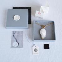 Example of necklace inside grey gift box, lid with porcelain monogram and felt protective cover. Included are care instructio